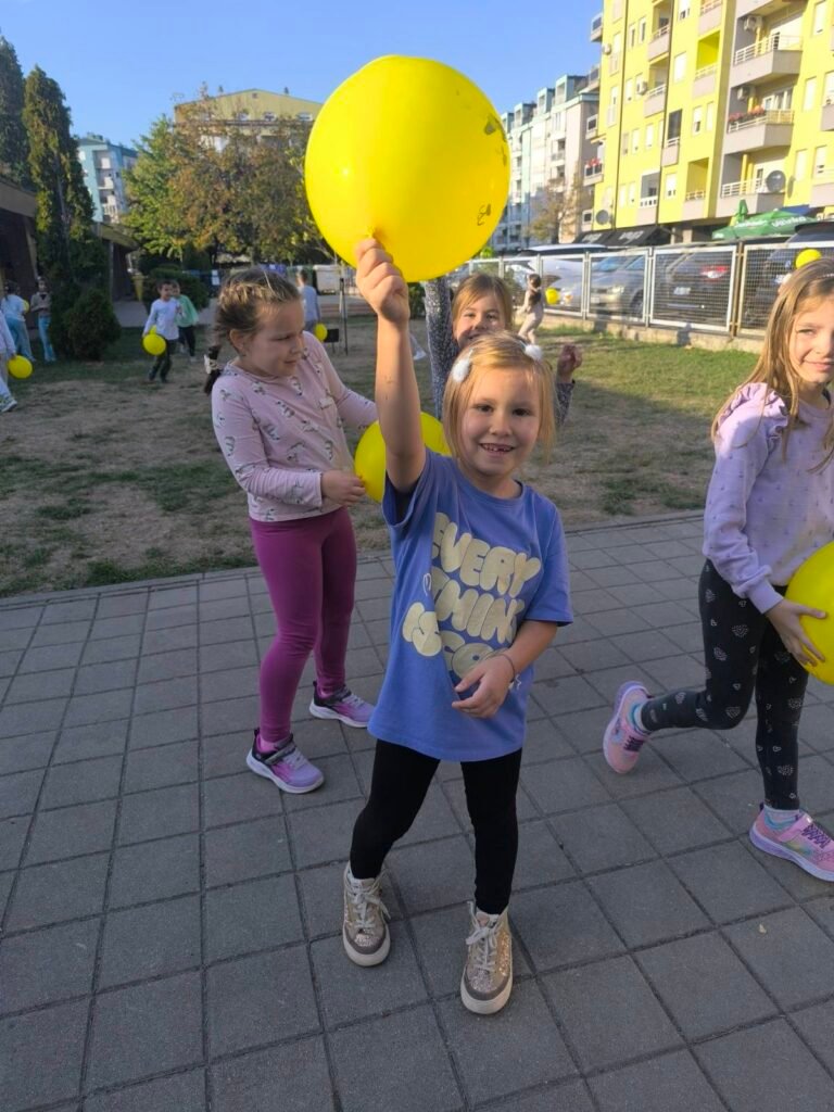 Дјеца се играју са балонима у школском дворишту"